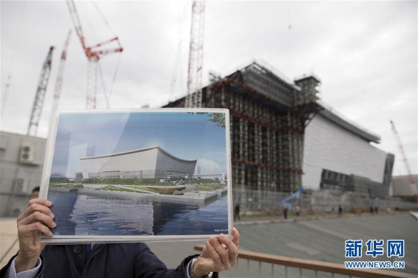 2月12日、東京「有明アリーナ」の建設現場で、完成予想図を手にする関係者。バレーボール競技とパラリンピックの車いすバスケットボールの試合がここで行われる計画。1月末の時点で51％が完成している（撮影・杜瀟逸）。 