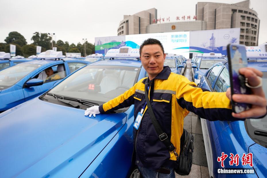 引き渡しセレモニーでメタノール車タクシーと記念撮影するタクシー運転手（撮影・賀俊怡）。