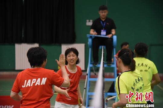 中日両国のバドミントン愛好者が試合後にハイタッチを交わす様子（撮影・鍾欣）。