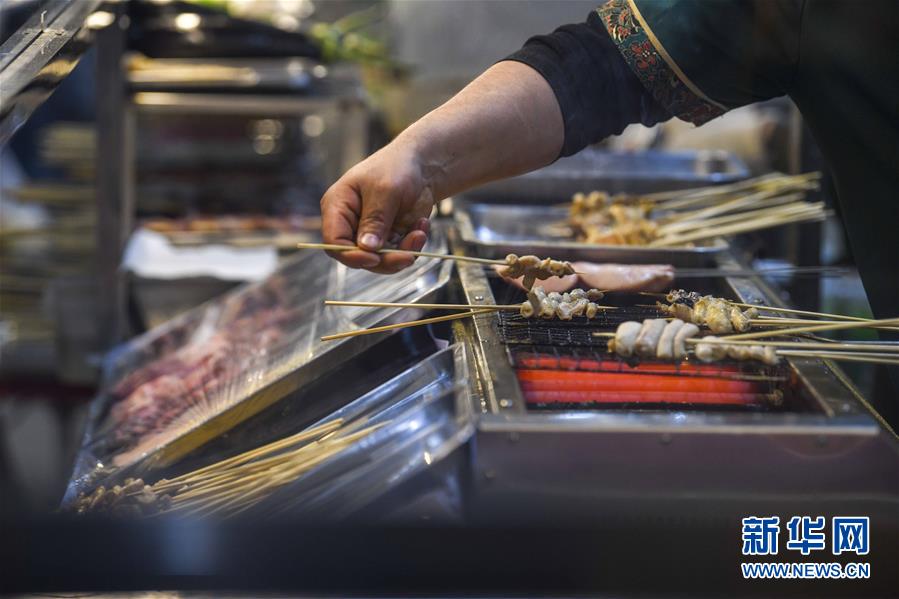 3月16日、ホータンナイトバザール環湖店で、串焼きを作る屋台の店主（撮影・ 趙戈）。