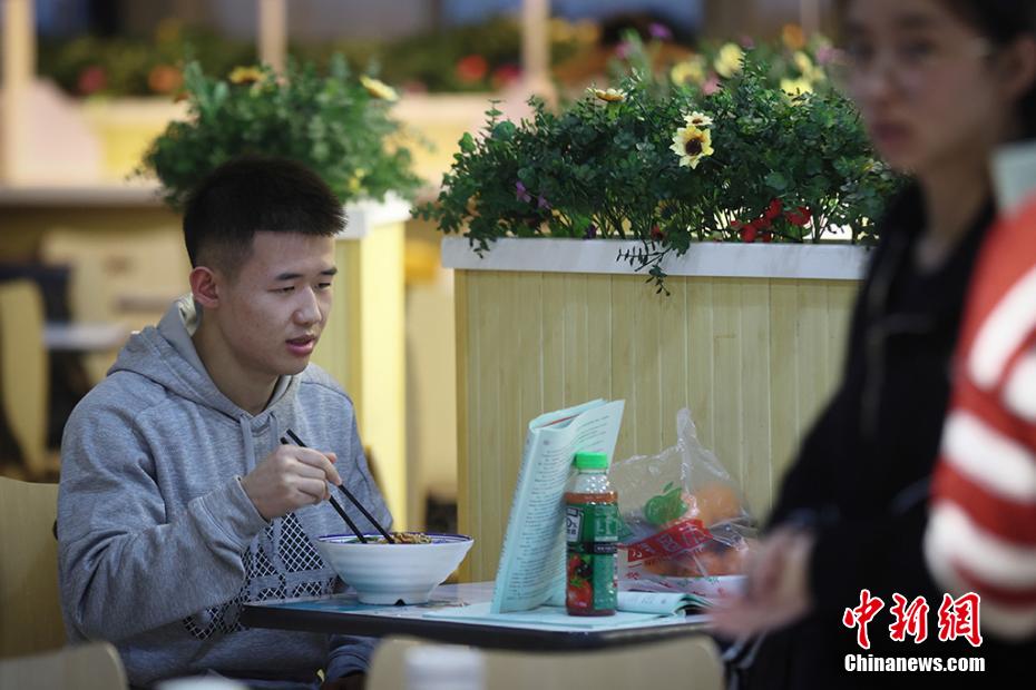 麺料理を食べながらも復習を続ける学生（撮影・泱波）。