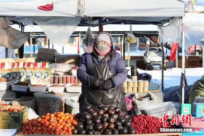 しっかり着込んで東北名物の凍果を売る漠河市の露店経営者（撮影・王景陽）。