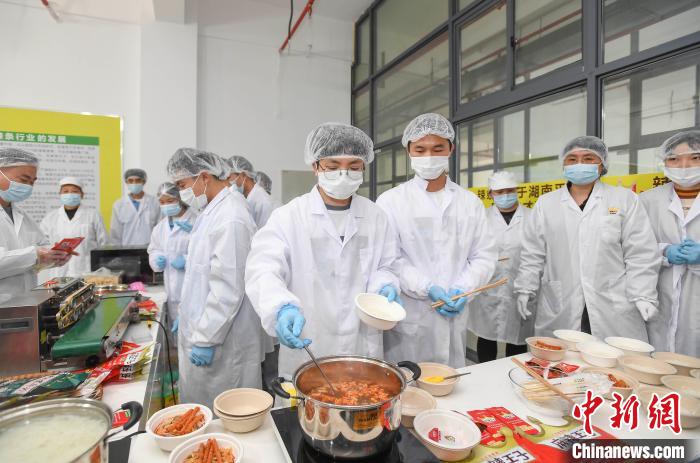 「ピリ辛タニシ麺」を作る辣条専攻クラスとタニシ麺学院の教員・学生（撮影・楊華峰）。