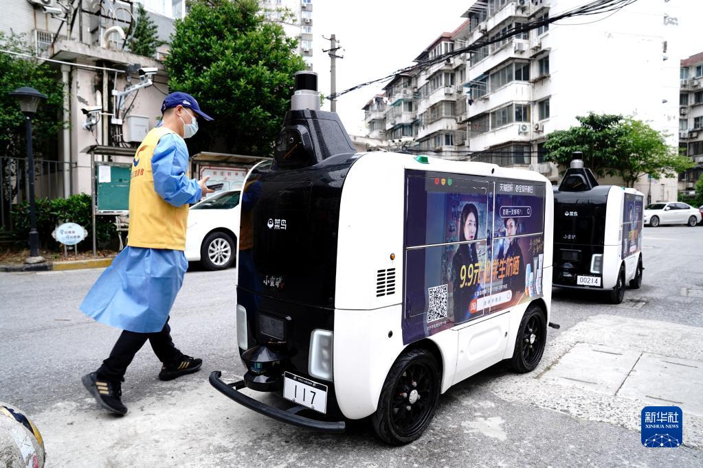 4月25日、コミュニティ入口で配送物を無人配送車に入れる上海市楊浦区長海路街道（エリア）浣紗小区（コミュニティ）の党員ボランティア（撮影・張建松）。