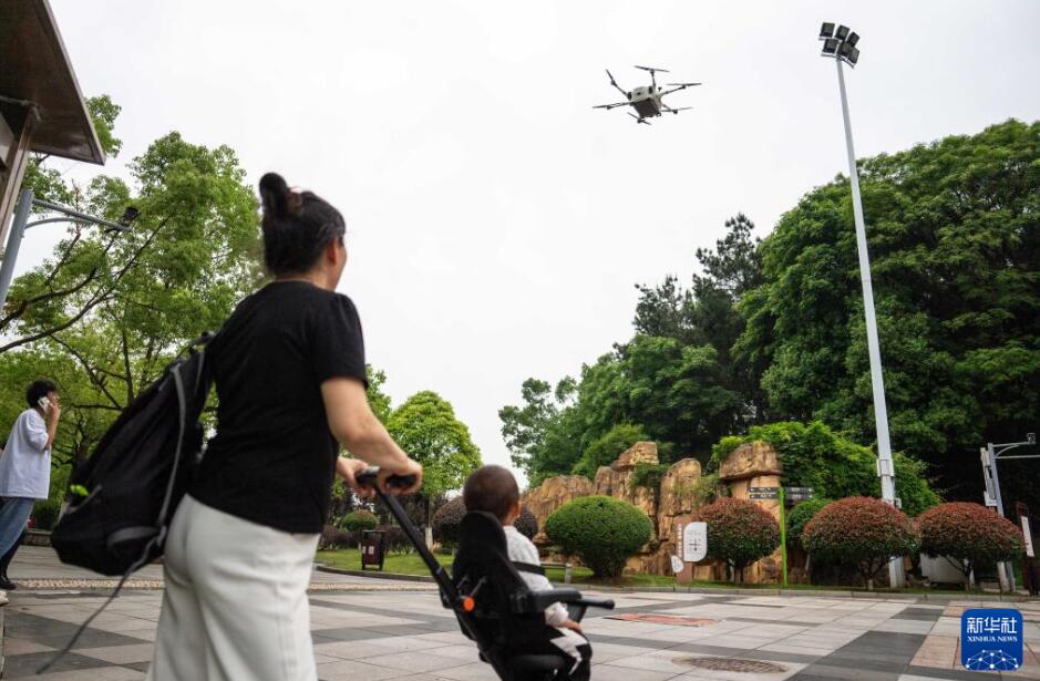 湖南省長沙県の市街地にある公園で、荷物を積んだドローンが着陸する様子を見守る市民（5月7日撮影・陳思汗）。