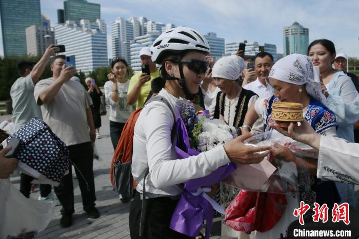 布爾蓮さんは新疆維吾爾（ウイグル）自治区烏魯木斉（ウルムチ）を自転車で出発して25日後の現地時間今月13日に、2000キロ以上離れたアスタナに到着。写真は現地の華人・華僑の大歓迎を受ける布爾蓮さん（撮影・単璐）。