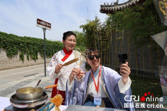 飴細工を体験する韓国人ブロガー・金峻範さん（写真右、撮影・賈親親）。